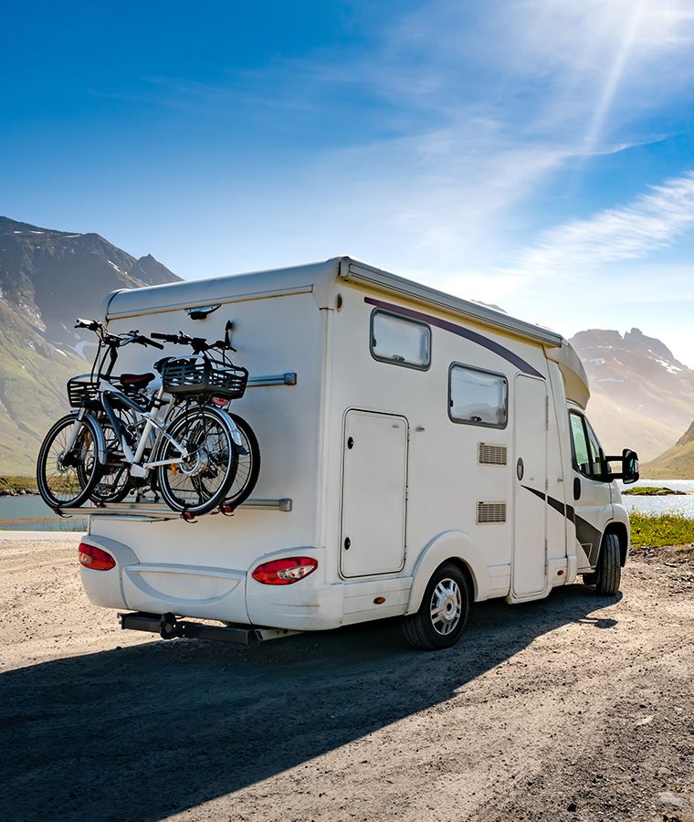 Ein Wohnmobil steht an einem See mit Blick auf hohe Berge.